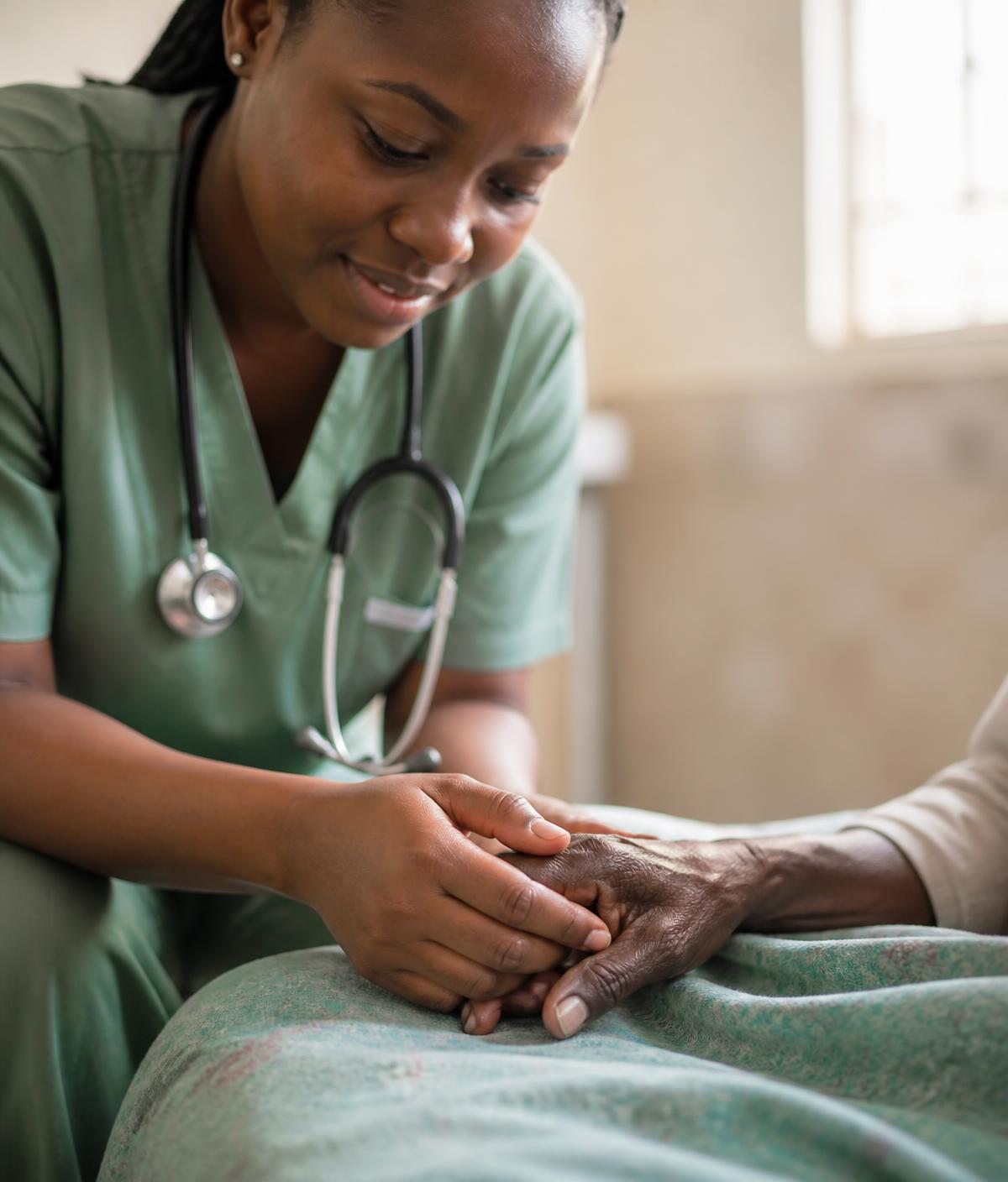 Nurse holding the hand of an elderly patient at the bedside